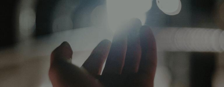 Hand reaching out into light